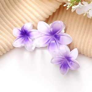 Gros plan sur une pince à cheveux fleur violette dégradée sur tissu beige côtelé