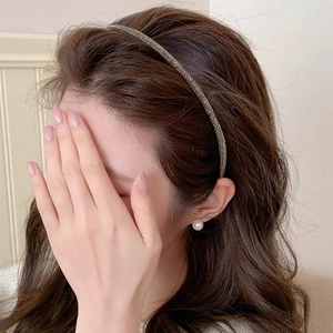 Detail of slim rhinestone headband with grey crystals worn on long dark hair
