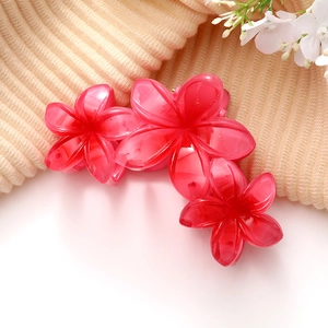 Détail macro d'une pince à cheveux florale en résine rouge sur tissu beige doux