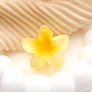 Frangipani acrylic hair claw clip with yellow gradient finish on beige knit texture