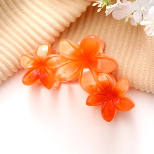 Détail de la grande pince à cheveux orange en forme de fleur de frangipanier en résine