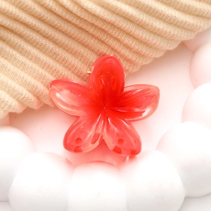 Macro detail of red frangipani hair claw clip with marble texture and metal spring