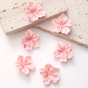 Pinces à cheveux fleurs de cerisier roses avec texture crème sur support en pierre