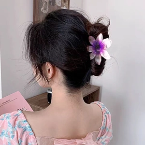 Grande pince à cheveux fleur dégradé violet portée sur un chignon pour vacances