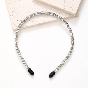 Detailed macro view of a thin headband featuring colorful pavé rhinestones on a beige stone