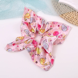 Detailed macro view of pink satin scrunchie featuring cute cartoon whale and heart patterns
