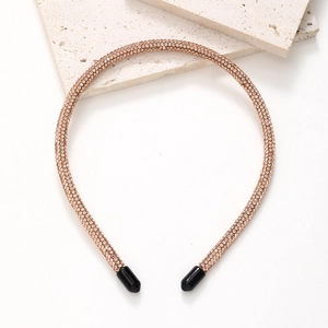 Macro detail of slim rose gold headband with sparkling rhinestones on stone background