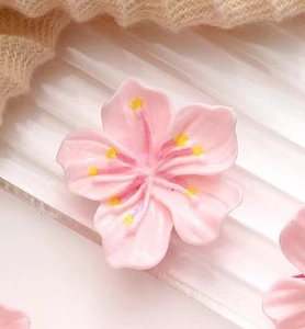 Détail macro d'une pince à cheveux cerisier 3D rose avec texture crémeuse et étamines jaunes