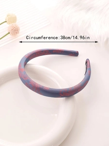Detail of blue satin paisley headband with soft non-slip lining on a white ceramic plate