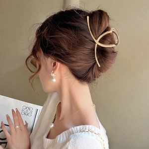 Minimalist golden shark hair claw clip shown on woman with elegant updo hairstyle