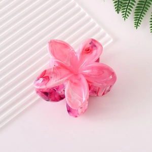 Close-up of frangipani flower hair claw clip with pink marble texture on pink background