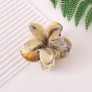 Detailed close-up of frangipani flower hair claw clip with marble texture on white background
