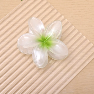 Macro view of pearlescent plumeria hair claw clip with gradient green center detailing