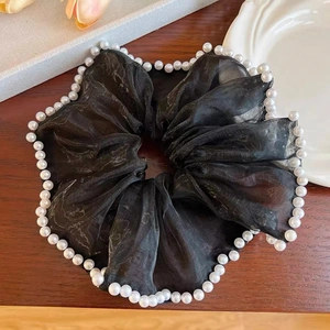 Elegant black organza scrunchie with white pearls on a rustic wood background