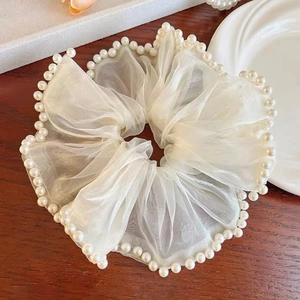 Elegant white organza scrunchie with pearl trim on a wooden background