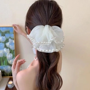 Close-up of elegant white organza bow scrunchie with delicate pearl trim on hair