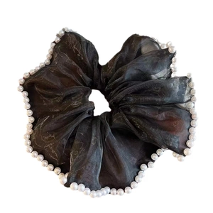 Close-up of elegant black organza scrunchie with white pearl trim detailing