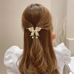 Detailansicht der goldenen Schmetterlings-Haarklammer mit Strass und Perlen in gewelltem Haar