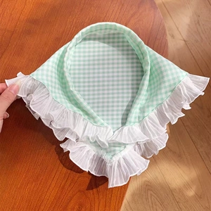 Close-up of a green plaid triangle headscarf with delicate white ruffled edge detail