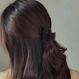Dettaglio di una molletta per capelli rettangolare nero opaco per acconciatura a metà