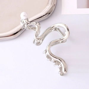 Macro shot of silver wave hair claw clip with pearl detail and polished finish