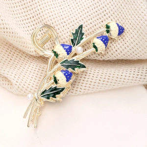 Detail of golden hair claw with blue enamel strawberries and white imitation pearls