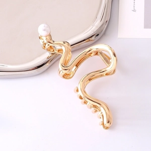 Detail view of wavy golden alloy hair claw clip with glossy finish and white pearl accent