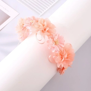 Détail de fleurs en tissu pêche pâle et nœud en ruban sur un bandeau floral doux et élégant