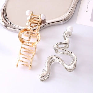 Elegant gold and silver metallic wave hair claws with pearl accents in a minimalist style