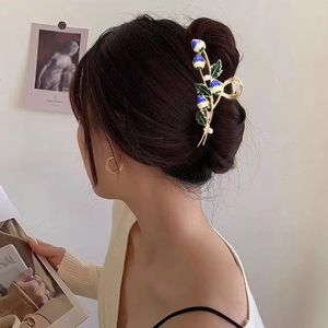 Detail view of a floral claw clip with blue berries and pearl on a model's hair
