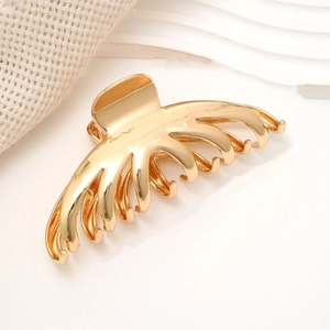 Close-up of polished gold alloy hair claw clip with sleek streamlined multi-tooth design