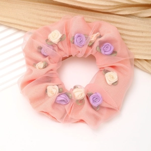 Detail van roze mesh haarelastiekje met delicate 3D-bloemen en groene blaadjes
