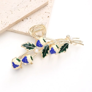 Detailed close-up of golden alloy strawberry hair claw clip with enamel and pearls
