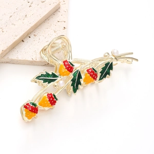 Detail of golden strawberry hair claw clip with red enamel fruit and white pearls
