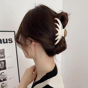Elegant wavy claw clip with cream finish and champagne gold edges worn by a model