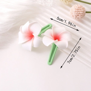 Détail de deux barrettes fleurs de frangipanier blanches avec centre rose et bec de canard