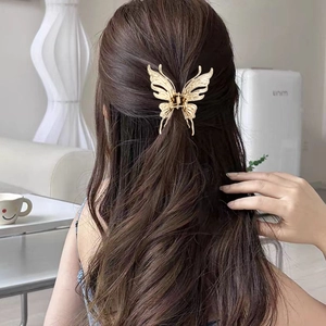 Détail d'une pince à cheveux papillon dorée avec strass portée sur une coiffure