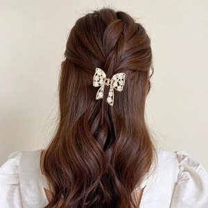 Détail d'une pince à cheveux papillon dorée avec strass sur des cheveux tressés