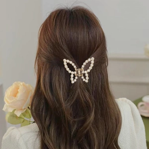 Détail d'une pince à cheveux papillon dorée avec strass dans une coiffure mi-haute