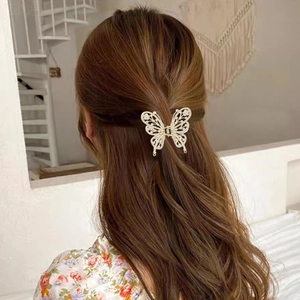 Détail d'une pince à cheveux papillon dorée avec strass blancs sur cheveux longs