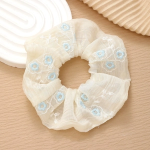 Detail of floral embroidery on a white chiffon scrunchie with blue flower patterns