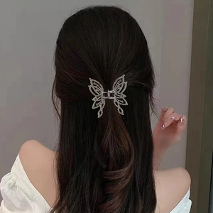 Détail macro d'une pince à cheveux papillon argentée avec strass portée en demi-queue