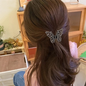 Détail d'une pince à cheveux papillon argentée avec strass portée en demi-queue