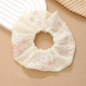 Detailed close-up of chiffon flower embroidery on an off-white elastic hair scrunchie
