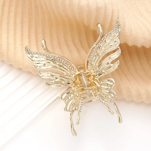 Pince à cheveux papillon dorée élégante avec strass sur un fond de texture délicate