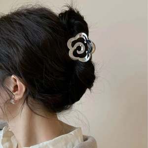 Pince à cheveux camélia en métal argenté avec centre noir sur cheveux bruns