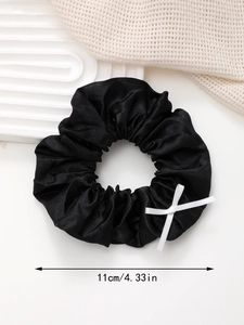 Vue détaillée d'un chouchou en satin noir de 11cm avec un élégant nœud en ruban blanc