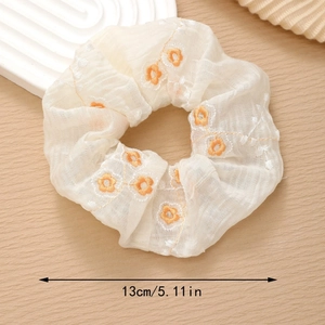 Detail showing a 13cm diameter off-white floral chiffon scrunchie with embroidery