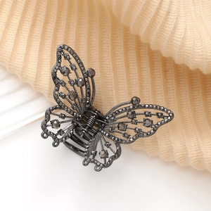 Détail d'une pince à cheveux papillon en métal noir avec des strass gris foncé brillants