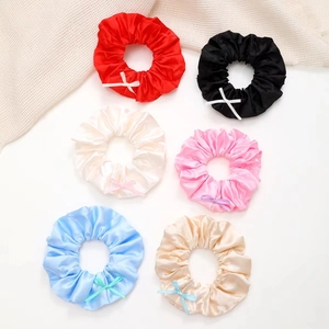 Lot de six chouchous en satin colorés avec petits nœuds sur fond blanc épuré